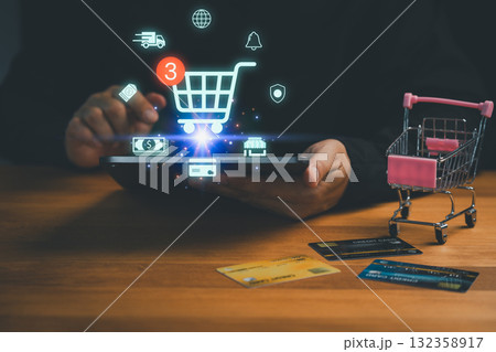 Customer using tablet with shopping cart icon, credit cards, and miniature trolley symbolizing online shopping, e-commerce, payment, retail, digital marketplace, delivery and modern technology. Customer using tablet with shopping cart icon, credit cards, and miniature trolley symbolizing online shopping, e-commerce, payment, retail, digital marketplace, delivery and modern technology. 132358917