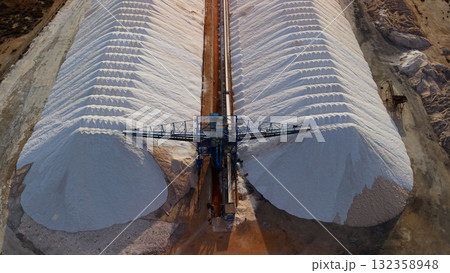 Aerial top view of massive salt piles and conveyor system at a salt production facility near Santa Pola, Spain. 132358948
