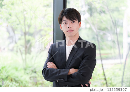 腕を組んで考えるスーツを着た若い20代男性 腕を組んで考えるスーツを着た若い20代男性 132359597