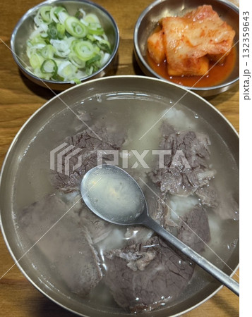 A hearty bowl of gukbap, a traditional Korean dish combining rich, flavorful broth with rice, often accompanied by tender meat and seasoned with green onions, garlic, and spicy sauces for a comforting A hearty bowl of gukbap, a traditional Korean dish combining rich, flavorful broth with rice, often accompanied by tender meat and seasoned with green onions, garlic, and spicy sauces for a comforting 132359643