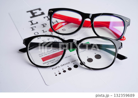Glasses on eye exam chart to test eyesight accuracy of reading. 132359689