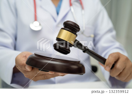Asian doctor holding court hammer for and crime law justice, forensic medicine. Asian doctor holding court hammer for and crime law justice, forensic medicine. 132359912