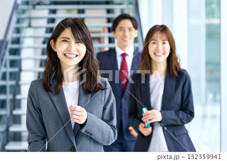 オフィスを笑顔で歩く3人のビジネスチーム オフィスを笑顔で歩く3人のビジネスチーム 132359941
