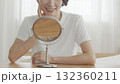 室内で鏡をみながら肌の調子を確認するミドル女性 132360211