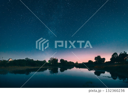 Night Starry Sky Above Lake River. Night Glowing Stars And Trees Woods Reflected In Water. Night Landscape. Panorama Night Starry Sky Above Lake River. Night Glowing Stars And Trees Woods Reflected In Water. Night Landscape. Panorama 132360236