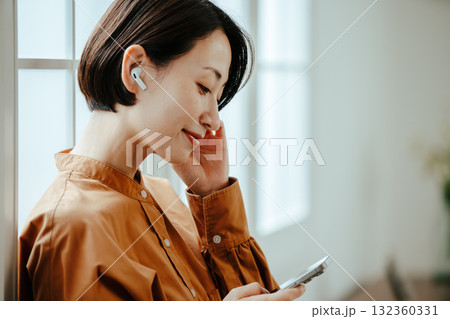 ワイヤレスイヤフォンをつけた40代女性 ワイヤレスイヤフォンをつけた40代女性 132360331
