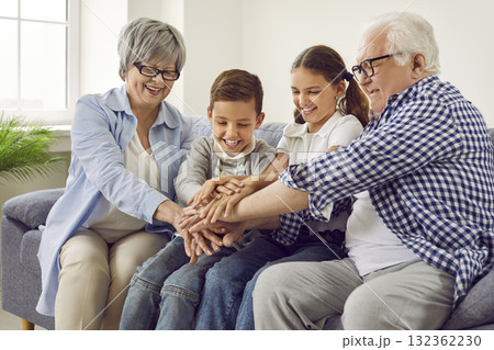 Happy grandparents and little children sitting on sofa and holding hands together 132362230