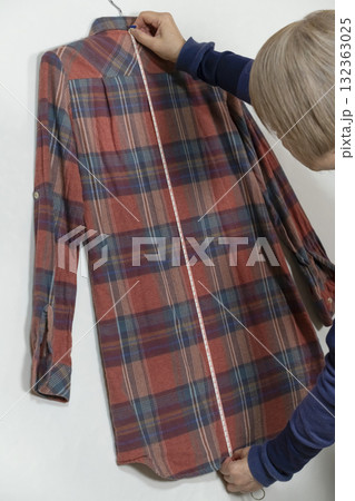 不要になった洋服をフリマサイトに出品するために洋服の採寸をするシニア女性 132363025