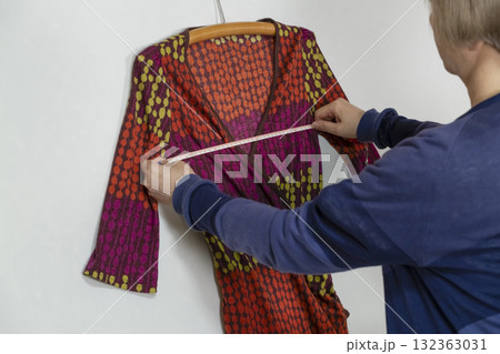 不要になった洋服をフリマサイトに出品するために洋服の採寸をするシニア女性 不要になった洋服をフリマサイトに出品するために洋服の採寸をするシニア女性 132363031