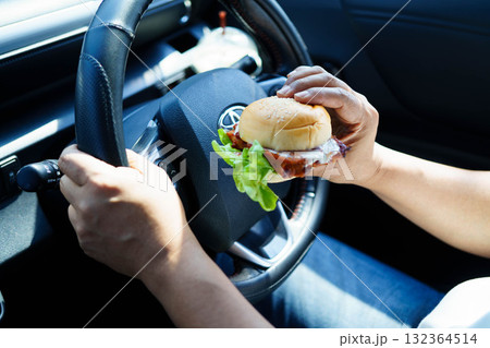 Bangkok, Thailand March 16, 2025 Asian woman driver hold and eat hamburger food in car. Bangkok, Thailand March 16, 2025 Asian woman driver hold and eat hamburger food in car. 132364514