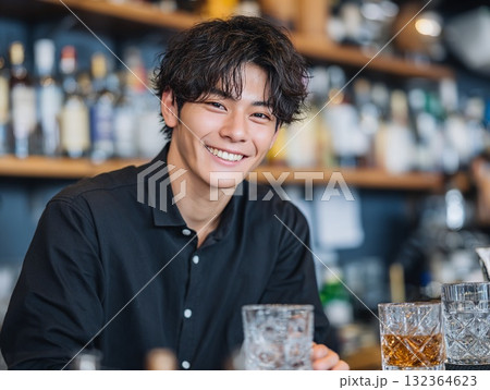 笑顔が素敵なバーテンダーの男性、カクテル提供の様子、接客業のイメージ 132364623