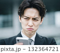 何かをみて困惑するビジネスマンの表情、スマホに注目 132364721