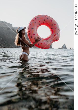 Woman, water, donut float, happy woman holding a donut float in the sea with rocky cliffs, enjoying summer vacation Woman, water, donut float, happy woman holding a donut float in the sea with rocky cliffs, enjoying summer vacation 132366914