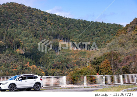 色づいた紅葉の山を背景に佇む四輪駆動車 132367727