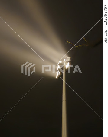 Spotlight beaming blue ray through foggy air in the dark Spotlight beaming blue ray through foggy air in the dark 132368767