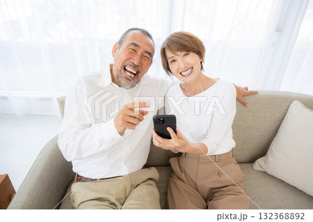 スマホを操作しながら笑うシニア夫婦 132368892