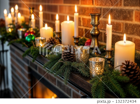 Holiday decorated fireplace mantel with evergreen garland candles mercury glass votives vintage ornaments and brass candlesticks creating warm festive atmosphere 132372434