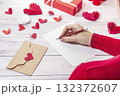 girl writes a love letter against the background of a gift and red hearts 132372607