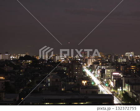 住宅街の夜景、光の筋が流れる大通りと無数の窓の灯り 132372755
