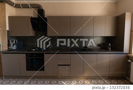 Modern Gray Kitchen Interior with Black Marble Backsplash and Stainless Steel Appliances: A Stylish Culinary Space for Contemporary Living. Modern Gray Kitchen Interior with Black Marble Backsplash and Stainless Steel Appliances: A Stylish Culinary Space for Contemporary Living. 132372838
