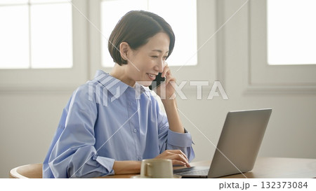 パソコンをする女性(携帯操作) 132373084