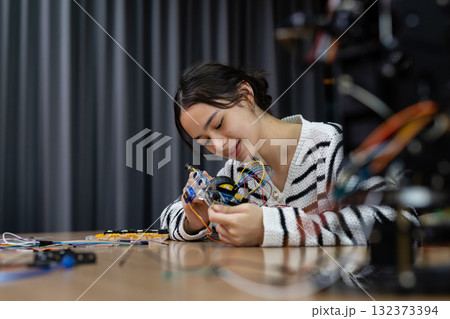 Student girl concentrates on assembling robotic car with wires and components at workshop. Engineering classroom with technology and enhancing creativity and learning. STEM education concept. Student girl concentrates on assembling robotic car with wires and components at workshop. Engineering classroom with technology and enhancing creativity and learning. STEM education concept. 132373394