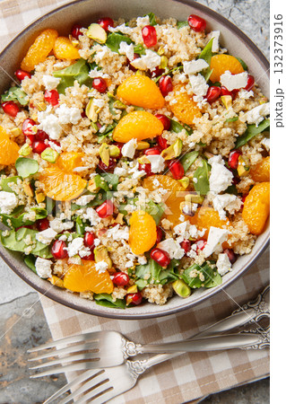 Winter Pomegranate Orange Quinoa Salad with spinach, feta, and pistachios closeup on the plate. Vertical top view Winter Pomegranate Orange Quinoa Salad with spinach, feta, and pistachios closeup on the plate. Vertical top view 132373916