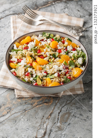 Winter Pomegranate Orange Quinoa Salad with spinach, feta, and pistachios closeup on the plate. Vertical 132373921