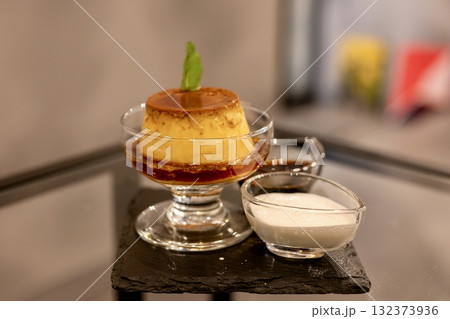 グラスプリンとソースが並ぶ上品なカフェデザート 132373936