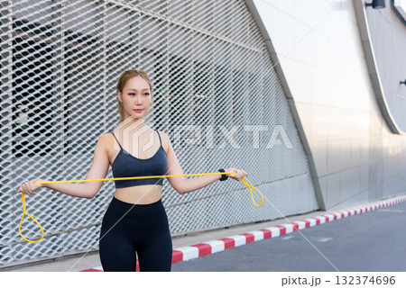 Fit young woman performs outdoor sport exercise workout, jump rope activity keeps people feeling fit, promotes healthy active lifestyle with stretching 132374696