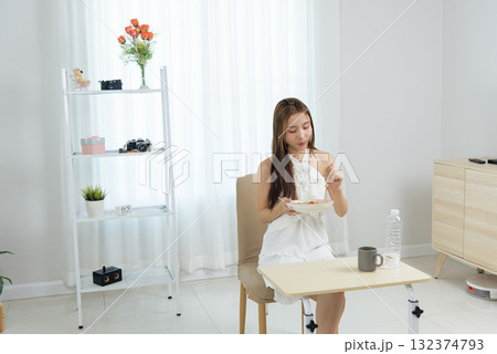 Young woman enjoying happy home activity, people eat healthy meal with chopsticks, relaxing indoors bright clean apartment, comfortable lifestyle moments at modern minimal living space 132374793