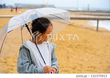 Asian girl in glasses with umbrella on the shore of the eastern sea Asian girl in glasses with umbrella on the shore of the eastern sea 132374913
