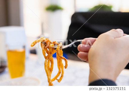 Lagman noodles on fork. man eats bucatini noodles. noodle with meat 132375151