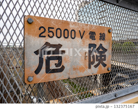 鉄道車両基地を跨ぐ跨線橋のフェンスに掲示された注意喚起「25000V 電線 危険」 132375167