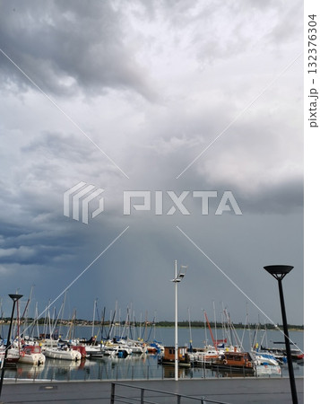 Yachts and sailboats moored at a pier under a stormy sky 132376304