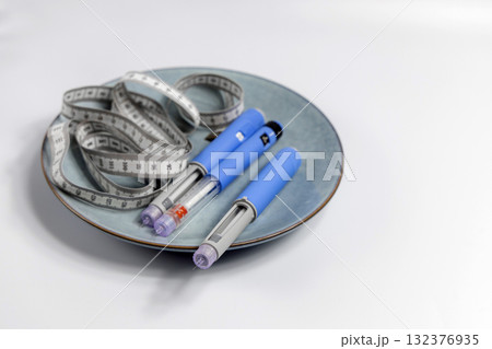 Ozempic Insulin injection pen for diabetics and weight loss on a plate with a measuring tape Ozempic Insulin injection pen for diabetics and weight loss on a plate with a measuring tape 132376935