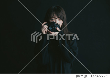 AI生成画像　黒背景のカメラを構える若い女性のポートレート 132377772