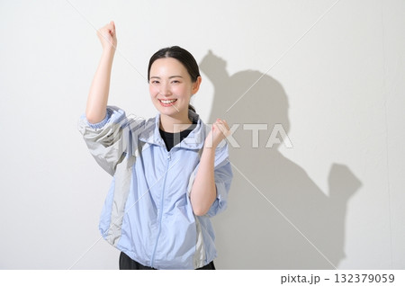 白背景でガッツポーズをするスポーツウェアの女性 白背景でガッツポーズをするスポーツウェアの女性 132379059