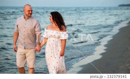 Couple enjoys a romantic evening stroll along the beach at sunset 132379141