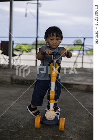 Photography of toddler determined while holding scooter, capturing energy and growth, suitable for parenting ads, lifestyle promotions, and childhood storytelling visuals. Photography of toddler determined while holding scooter, capturing energy and growth, suitable for parenting ads, lifestyle promotions, and childhood storytelling visuals. 132380013