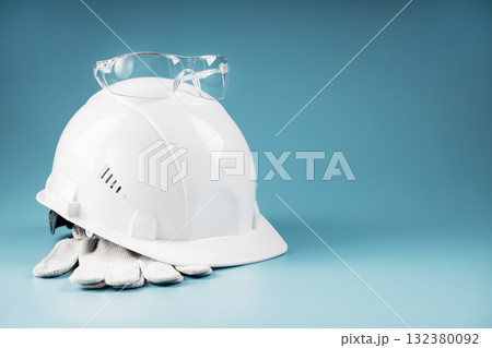 White protective helmet with glasses and gloves on a blue background White protective helmet with glasses and gloves on a blue background 132380092