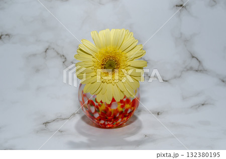 暖色でガラスの一輪挿しに挿した一輪の黄色いガーベラの花(中央配置正面向き) 暖色でガラスの一輪挿しに挿した一輪の黄色いガーベラの花(中央配置正面向き) 132380195