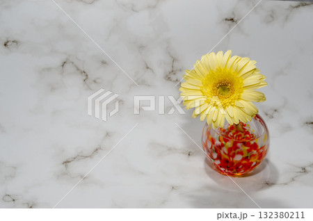 暖色でガラスの一輪挿しに挿した黄色いガーベラの花（右配置前向き） 132380211