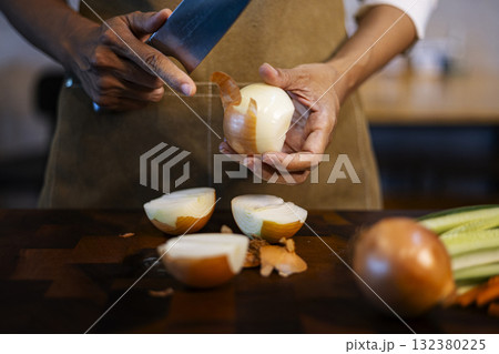 Chef Is Peeling An Onion In Her Hand, detailed cooking scene perfect for culinary ads, recipe videos, cooking tutorials, and restaurant promotions. 132380225