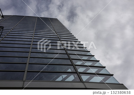 Sky And Clouds Mirroring On Modern Skyscraper, Sky and clouds reflect stunningly on a sleek skyscraper's glass facade, perfect for promoting cutting-edge urban architecture. 132380638