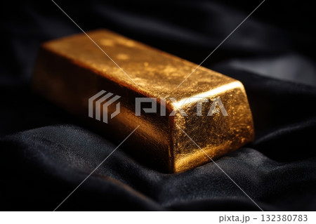 Gold bar resting on dark fabric surface 132380783