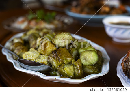 Grilled Eggplant On Party Table, A tender grilled eggplant sits on a lively party table, surrounded by vibrant appetizers, ideal for a culinary photo capture or a festive snack display. 132381039