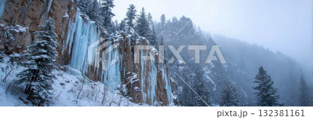 Stalactites of ice dangle from the roof of a cave, reflecting cold blue tones. The ground is rocky, creating a chilly winter scene filled with natural beauty, banner 132381161