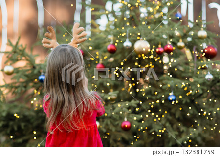 Christmas in july. Child waiting for Christmas in wood in summer. portrait of little girl in red dress decorating christmas tree. winter holidays and people concept. Merry Christmas and Happy Holidays 132381759