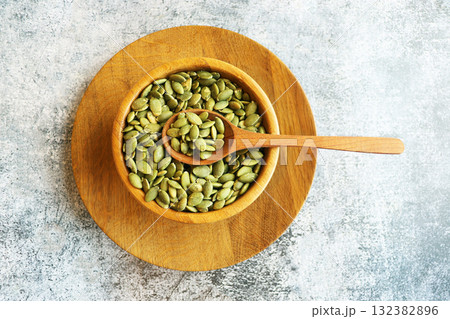 Bowl and spoon of peeled pumpkin seeds on grey marble table 132382896